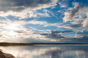 Beautiful sunset on the lake, the clouds reflected in the water. Surface on the lake. Russia, Karelia. Wide photo
