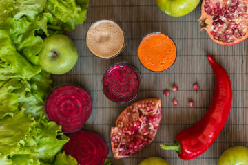 three glasses of different fresh juice. Beet, carrot and apple juices on grey wood background