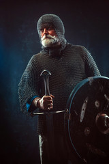Powerful bearded knight with the sword on the dark background