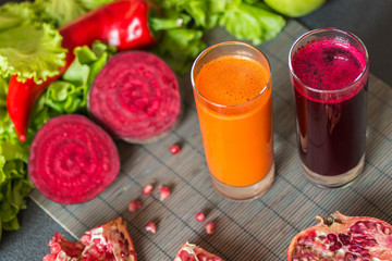 two glasses of different fresh juice. Beet and carrot juices on grey wood background