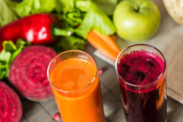 two glasses of different fresh juice. Beet and carrot juices on grey wood background