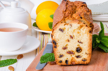 Lemon pound cake with dried cranberries and raisins on white wooden background