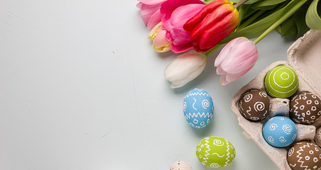 Painted easter eggs and bouquet of spring tulips closeup on a light blue background with space for congratulation
