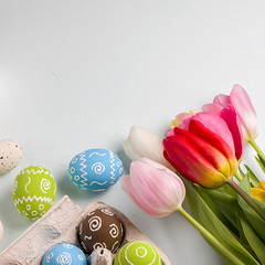 Painted easter eggs and bouquet of spring tulips closeup on a light blue background with space for congratulation