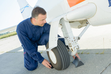 Mechanic putting chocks around wheel of aircraft
