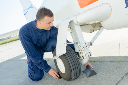 Mechanic putting chocks around wheel of aircraft
