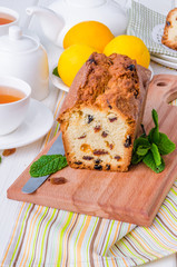Lemon pound cake with dried cranberries and raisins on white wooden background