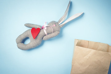 Easter bunny in a paper bag. Rabbit. Blue background. Easter ideas. Easter eggs. Space for text. Toned image. Trendy toning.