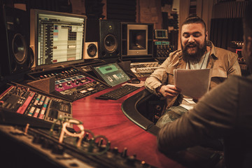 Sound engineer and musicians working in boutique recording studio.