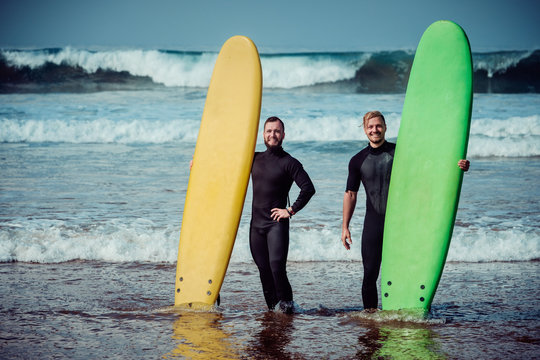 Surfer Beginner And Instructor On A Beach With A Surfboards