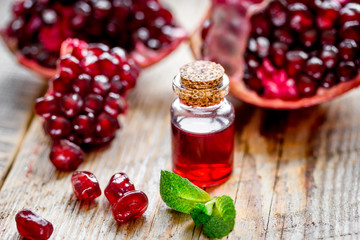sliced pomegranate and extract in glass on wooden background