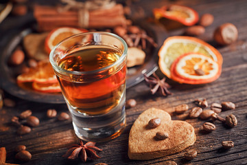 Whiskey or liqueur, cookies, spices and decorations on wooden background.