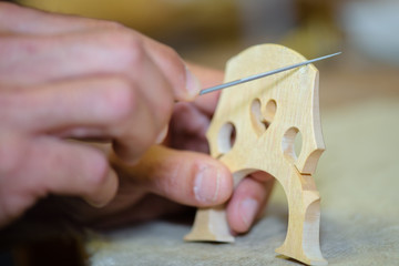 Closeup of craftsman making musical instrument bridge