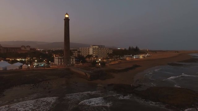 Aerial view of resort on the coast of Gran Canaria with Maspalomas Lighthouse at night. Active lighthouse of 19th century