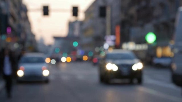 Cars and walking people on the street in the city at night with blurred background.