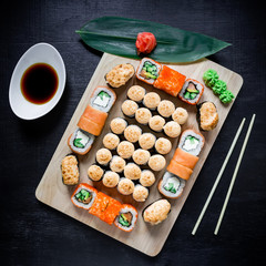 Set of traditional japanese food on a dark background. Sushi rolls and wasabi, ginger. Top view. Flat lay