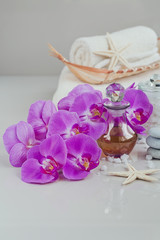 Fototapeta na wymiar Composition of spa treatment with perfume or aromatic oil bottle surrounded by purple orchids flowers.