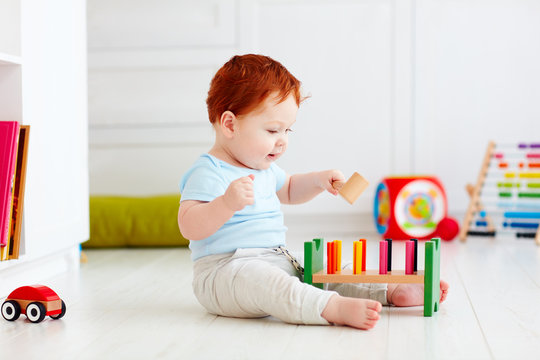 happy infant baby boy playing with toys at home