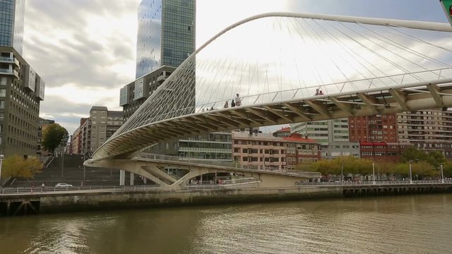 People walking over glass construction of Zubizuri bridge in Bilbao, Spain