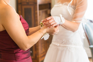 Obraz na płótnie Canvas Bridesmaid is helping the bride to buttoning wedding dress