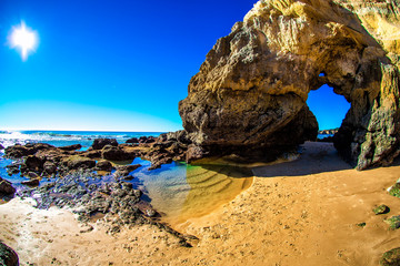 Fototapeta premium Rock with an arch on the beach by the ocean. Praia da Rocha, Portimao, Algarve, Portugal.