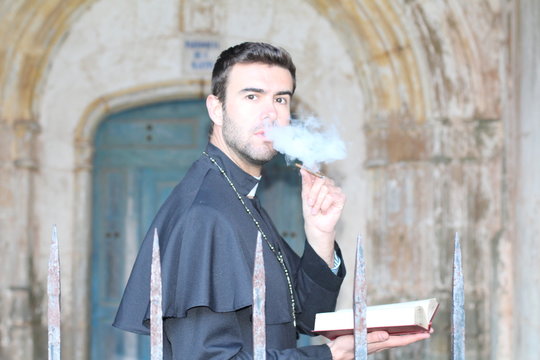 Handsome young priest smoking close up