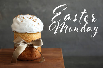 Text EASTER MONDAY on background. Traditional cake on wooden board