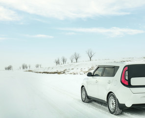 Fototapeta na wymiar Modern car driving on snowy winter road