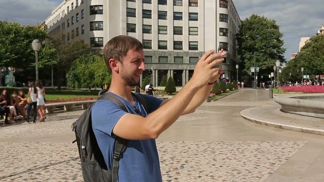 Curious tourist taking photos of beautiful Bilbao city on smartphone camera