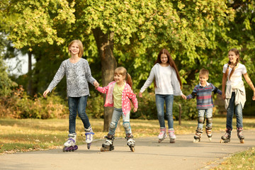 Fototapeta premium Cheerful children on roller skates in park
