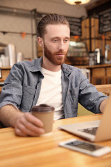 Handsome young man working on computer at cafe