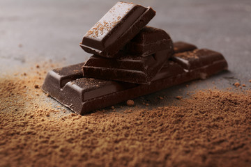 Chocolate with cocoa powder on grey background