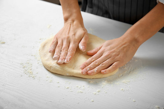 Woman hands making dough for pie on kitchen table