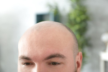 Bald adult man on blurred background, closeup