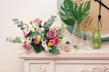 Beautiful composition with fresh flowers and vintage clock on mantelpiece