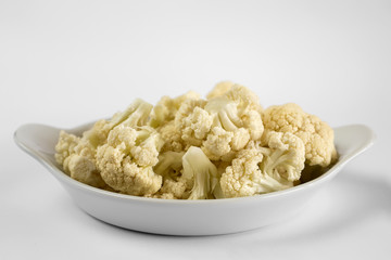 Cauliflower slices on a white plate on a white background