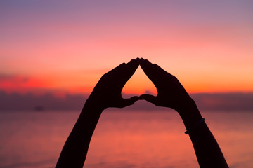 Heart shape with hands at sunset background