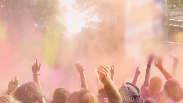 Excited people enjoying Holi festival, dancing and throwing powder paint