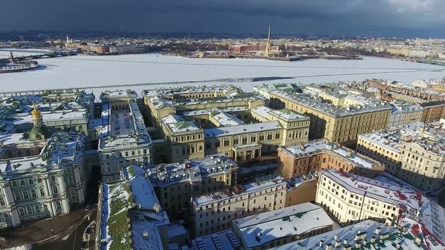 Aerial view at frozen Neva river and the Peter and Paul Fortress from the Palace Square. Flight over snowy roofs of ancient houses. St. Peterburg, Russia