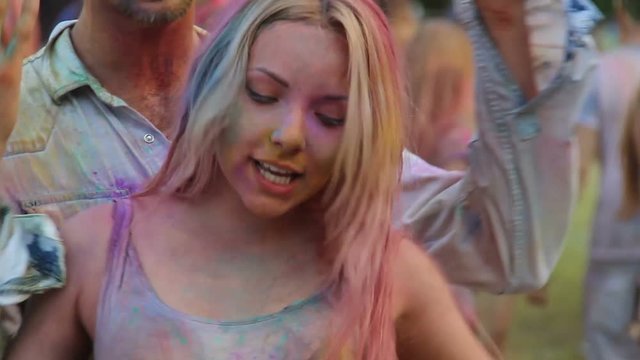 Beautiful female kissing boyfriend at Holi fest, couple dancing at cool party