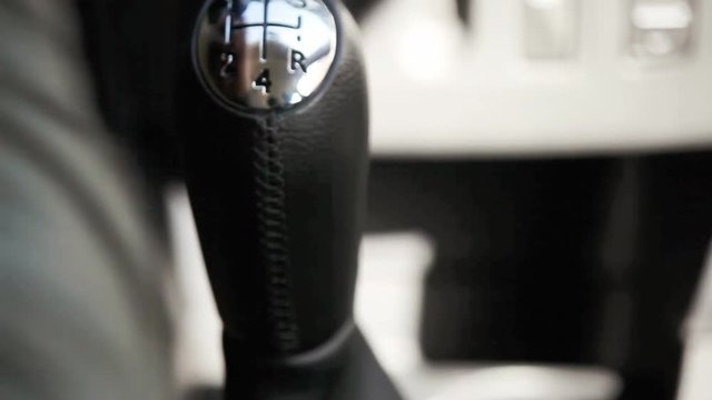 The hand of a man shifting the gearshift from number one to five.
