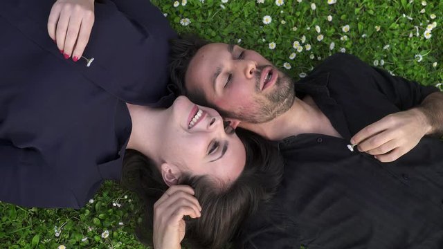 Romantic couple lying on the lawn talking amiably