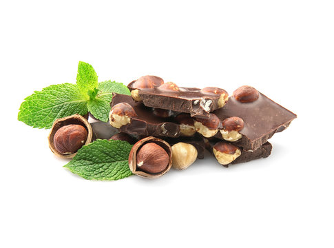 Broken chocolate pieces with nuts and mint leaves, isolated on white