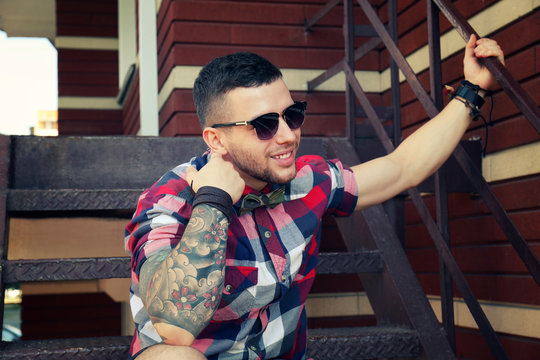 Young tattooed man posing on stairs, outdoor