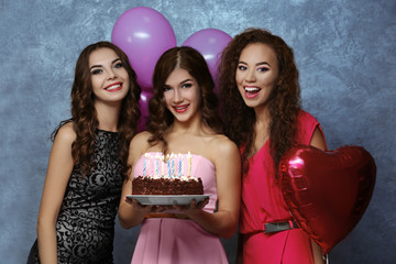 Beautiful young women with birthday cake near grey textured wall