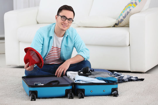 Handsome Young Man Packing Suitcase At Home