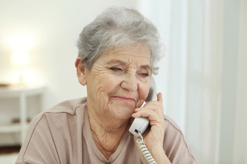 Elderly woman talking by telephone at home