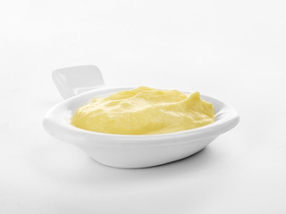 Creamy cheese in small modern saucer with comfortable handle, isolated on white