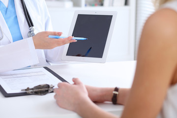 Close up of a doctor and  patient hands while phisician pointing into tablet computer monitor....