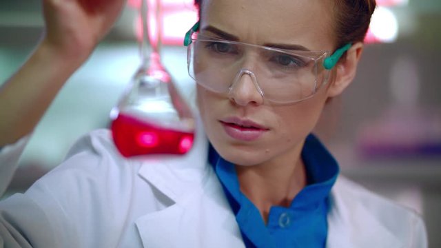 Medical researcher in medical lab. Close up of female lab researcher doing medical research. Woman scientist. Pharmaceutical research. Medical scientist doing laboratory research. Liquid in lab flask